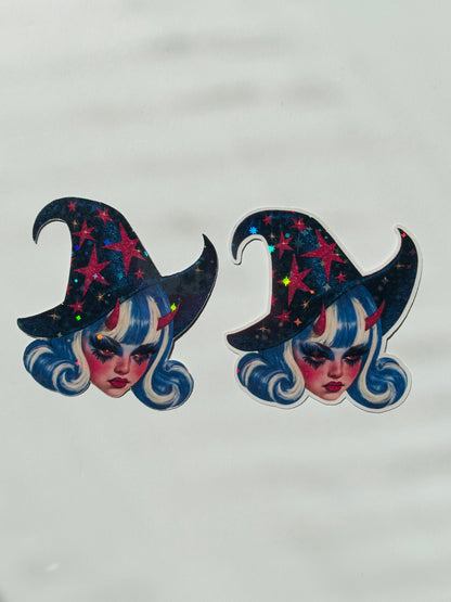 Two identical witch hat stickers with holographic star details, featuring a stylized face with blue hair, displayed on a light gray background.