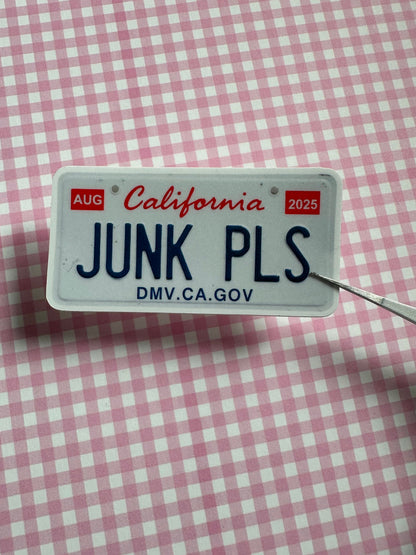 Novelty license plate with 'JUNK PLs' text on a pink and white checkered background