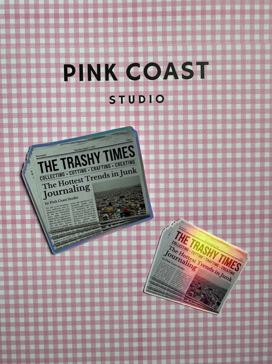 Two 'The Trashy Times' newspapers on a pink checkered background with 'Pink Coast Studio' branding.
