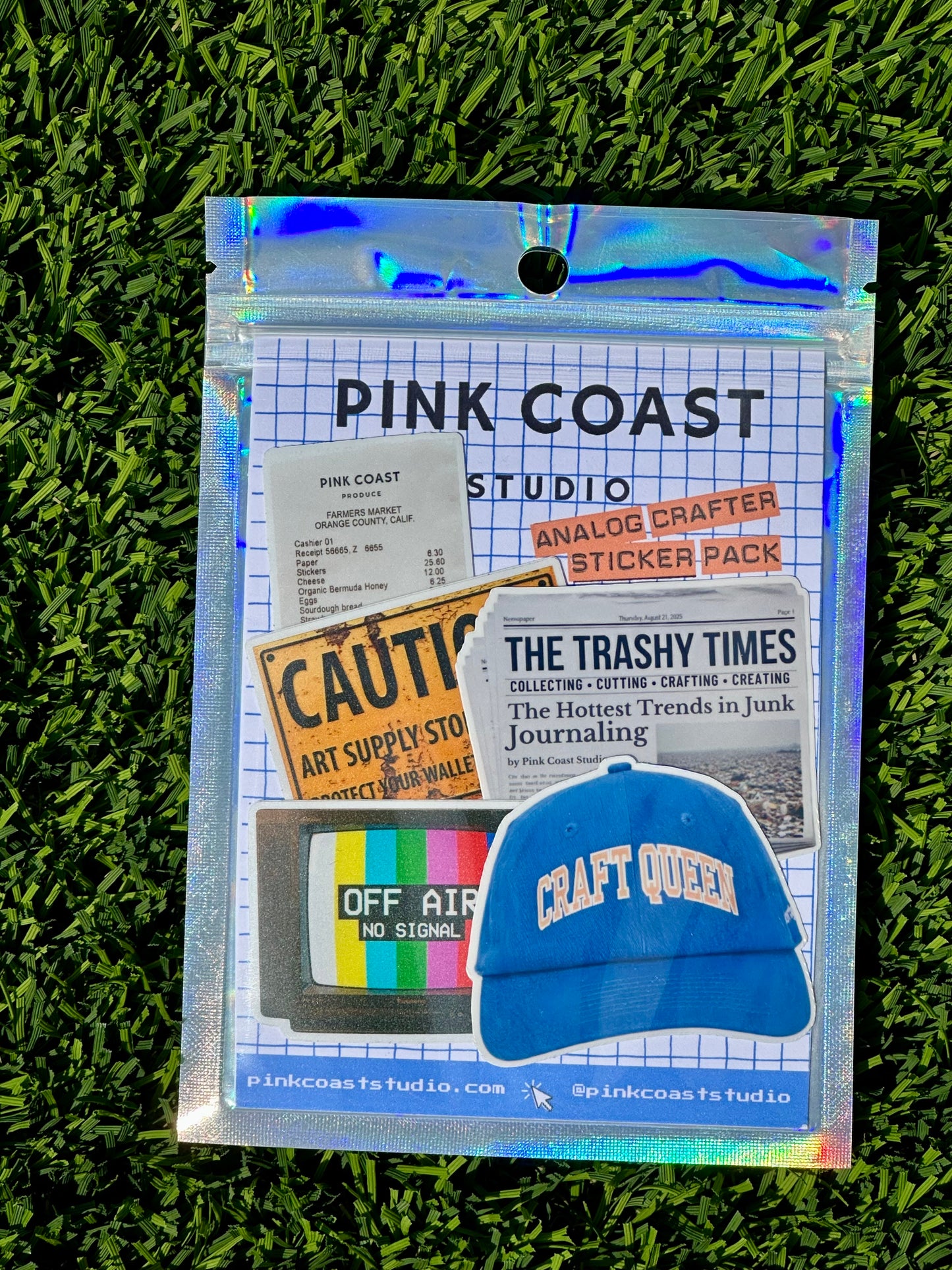 Pink Coast Studio sticker pack with a blue cap on a grass background