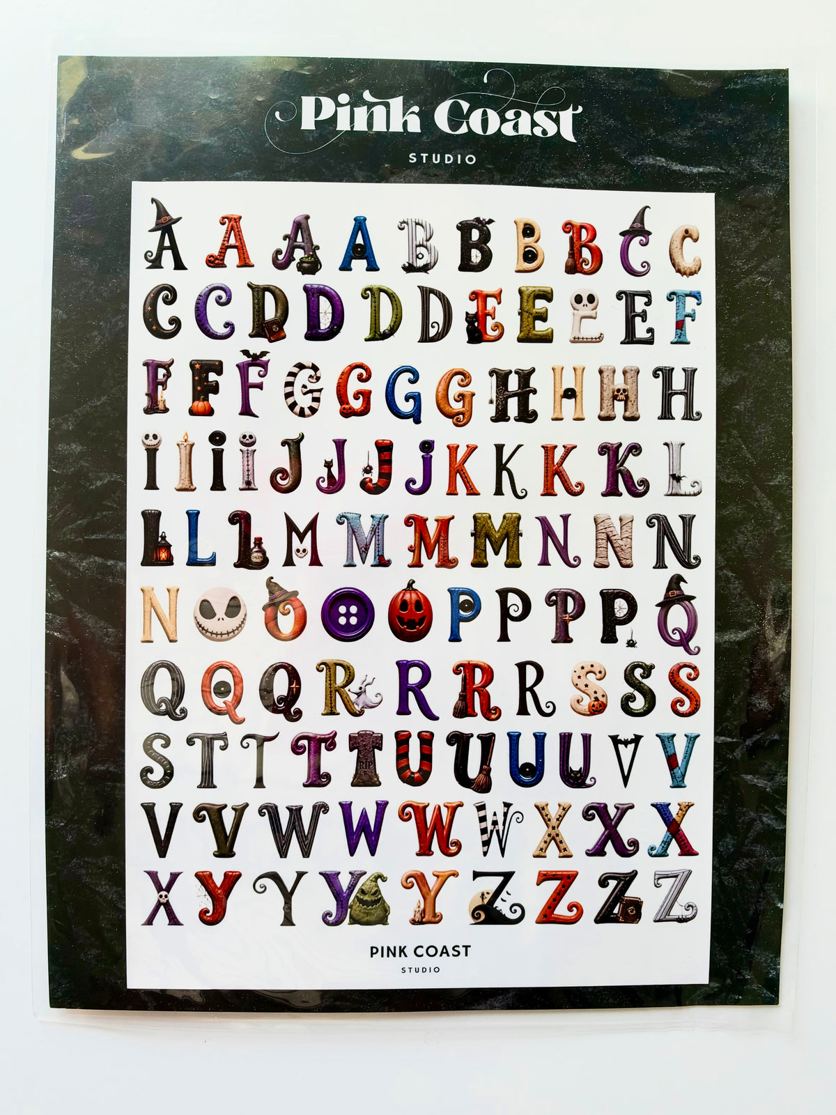 Pink Coast Studio alphabet stickers featuring Halloween-themed letter designs, displayed on a black backing card against a white background.