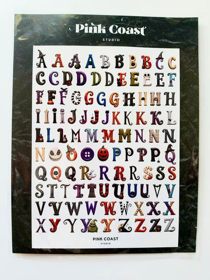 Pink Coast Studio alphabet stickers featuring Halloween-themed letter designs, displayed on a black backing card against a white background.